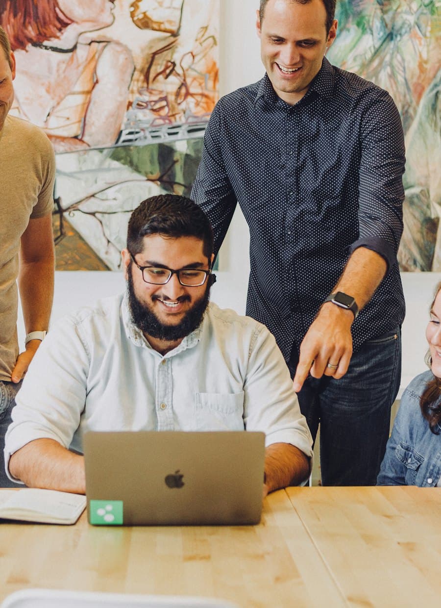 Equipe de agência reunida em volta de um notebook