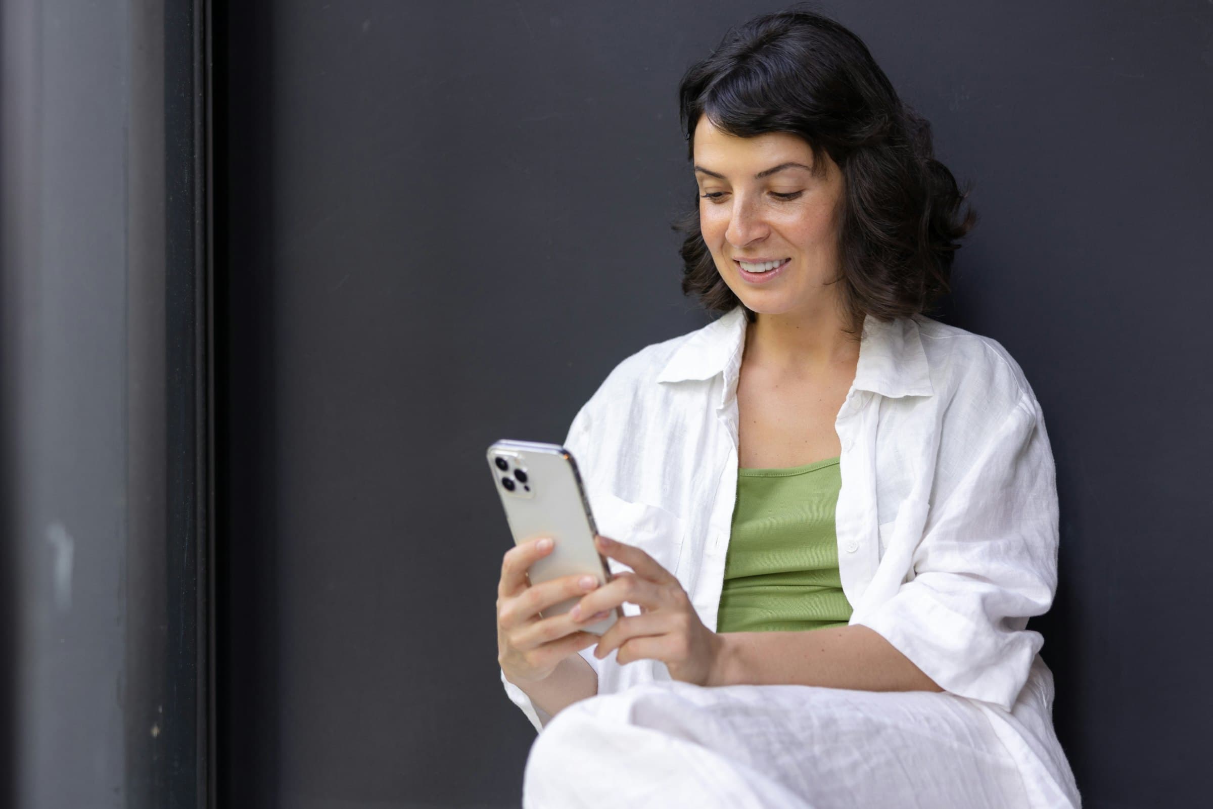 Profissional de jaleco sorrindo enquanto lê o celular